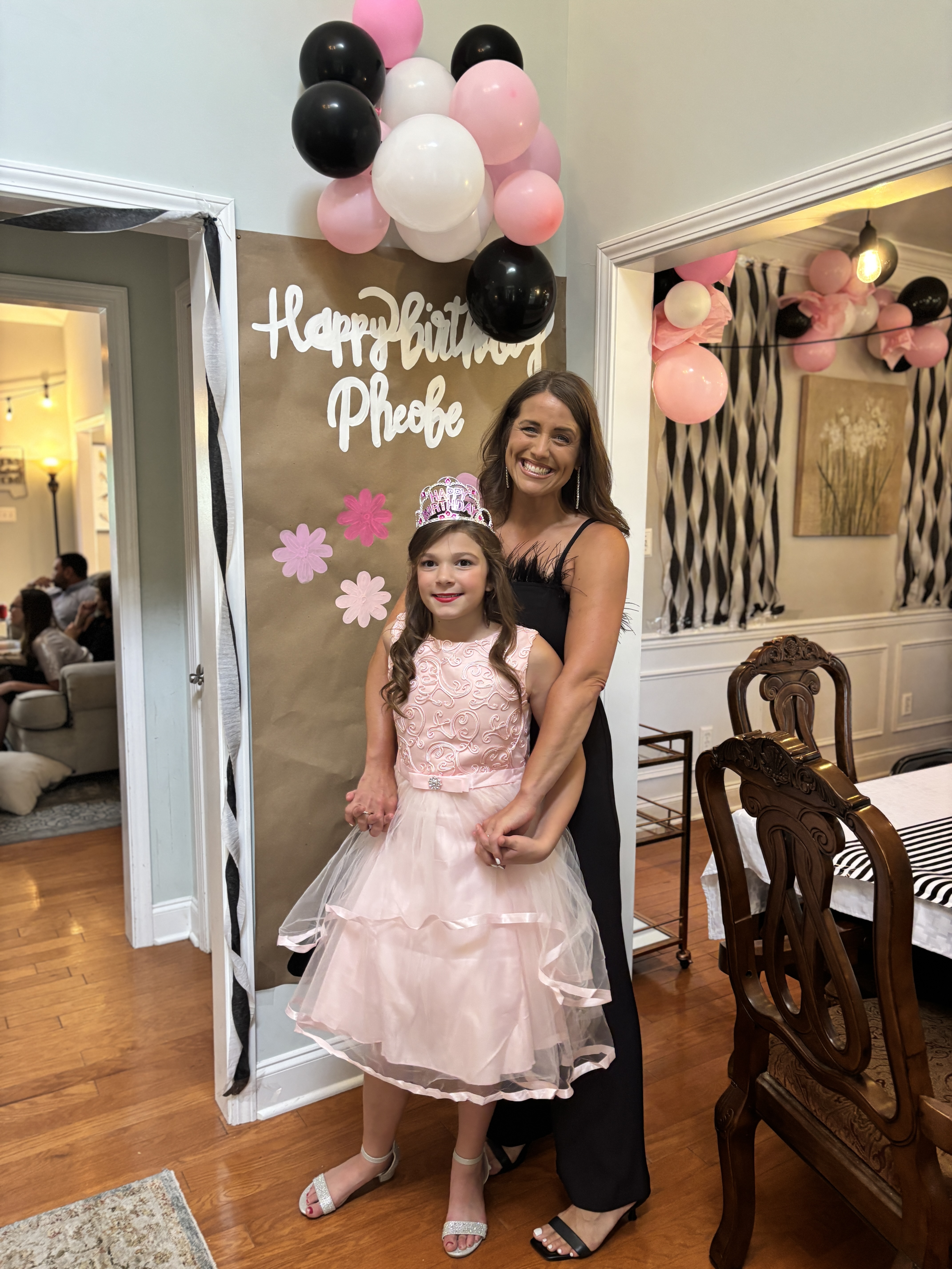 Coordinator with birthday girl in front of a handpainted birthday banner on brown craft paper