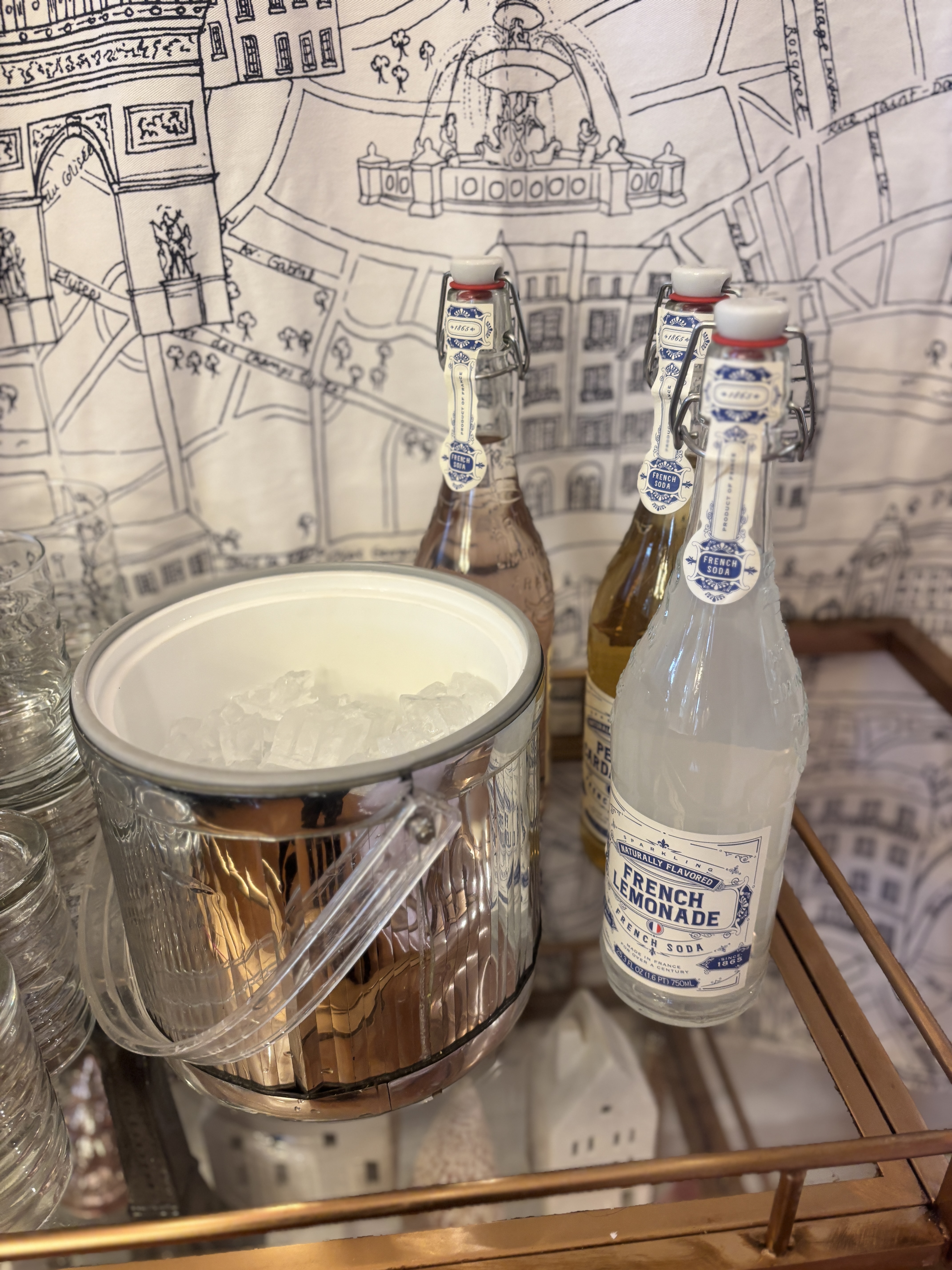 Parisian fabric backdrop behind a silver ice bucket and French sodas