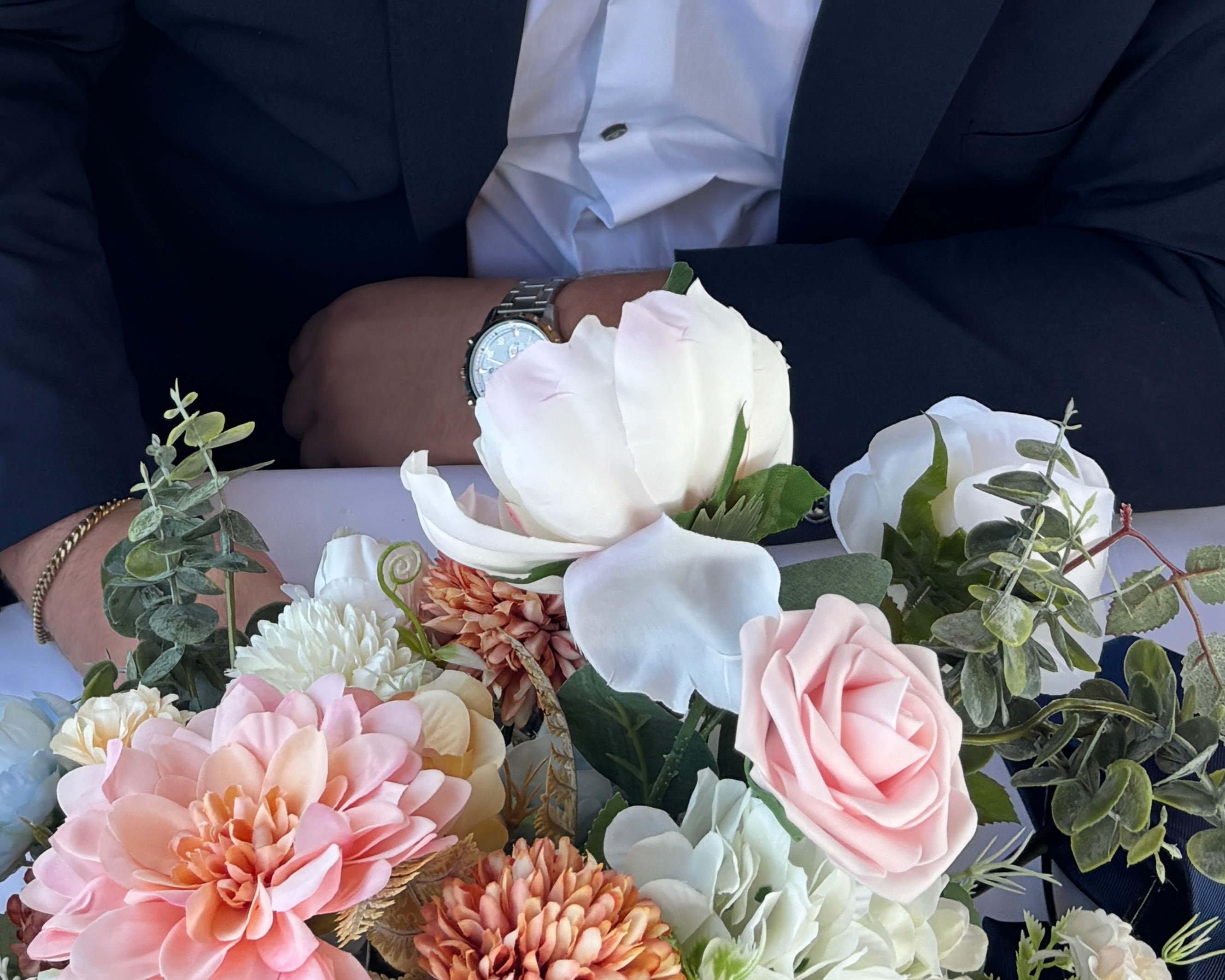 groomsman in tux beside a faux floral arrangement