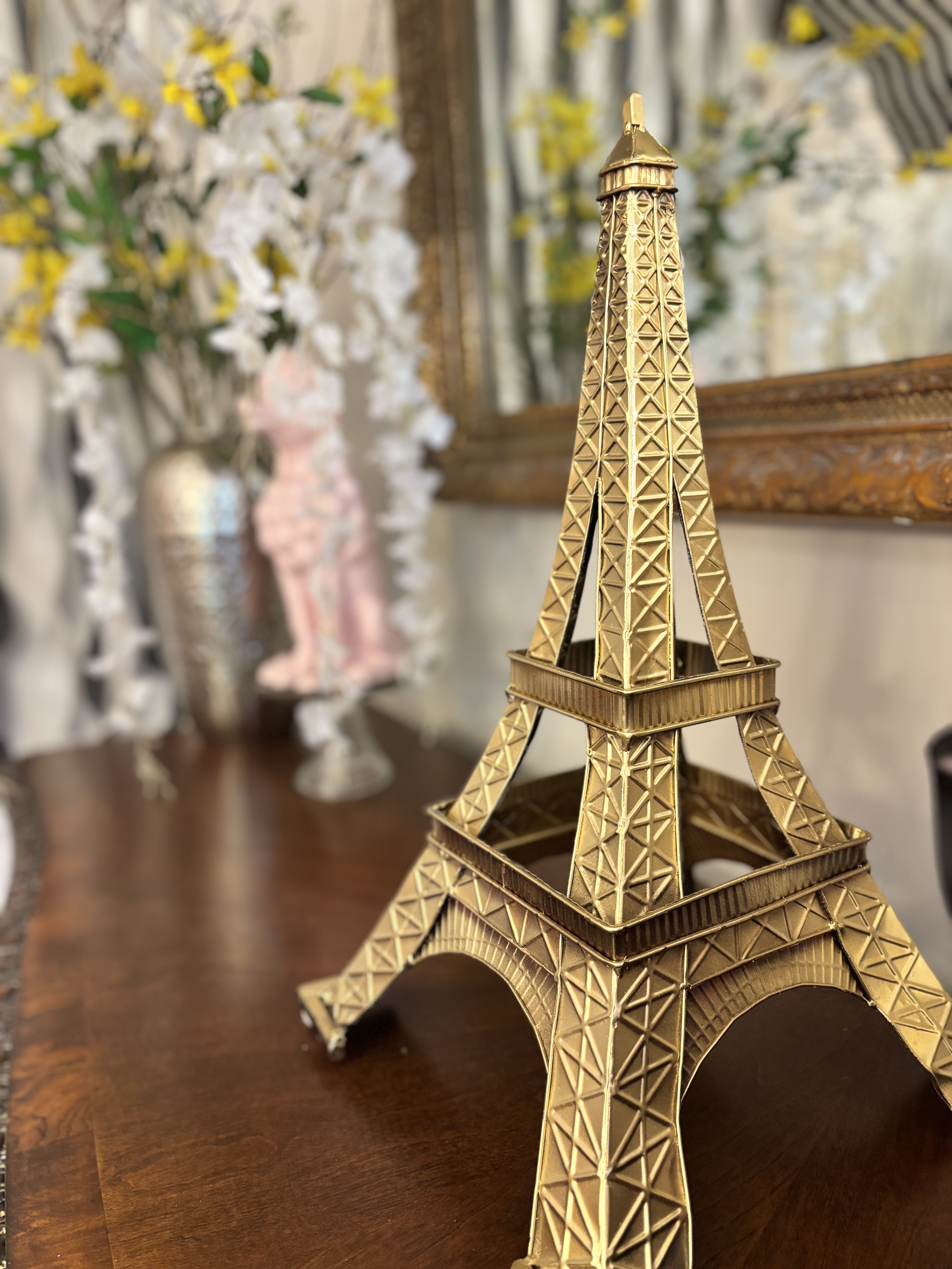 A gold Eiffel Tower statue with flowers in the background