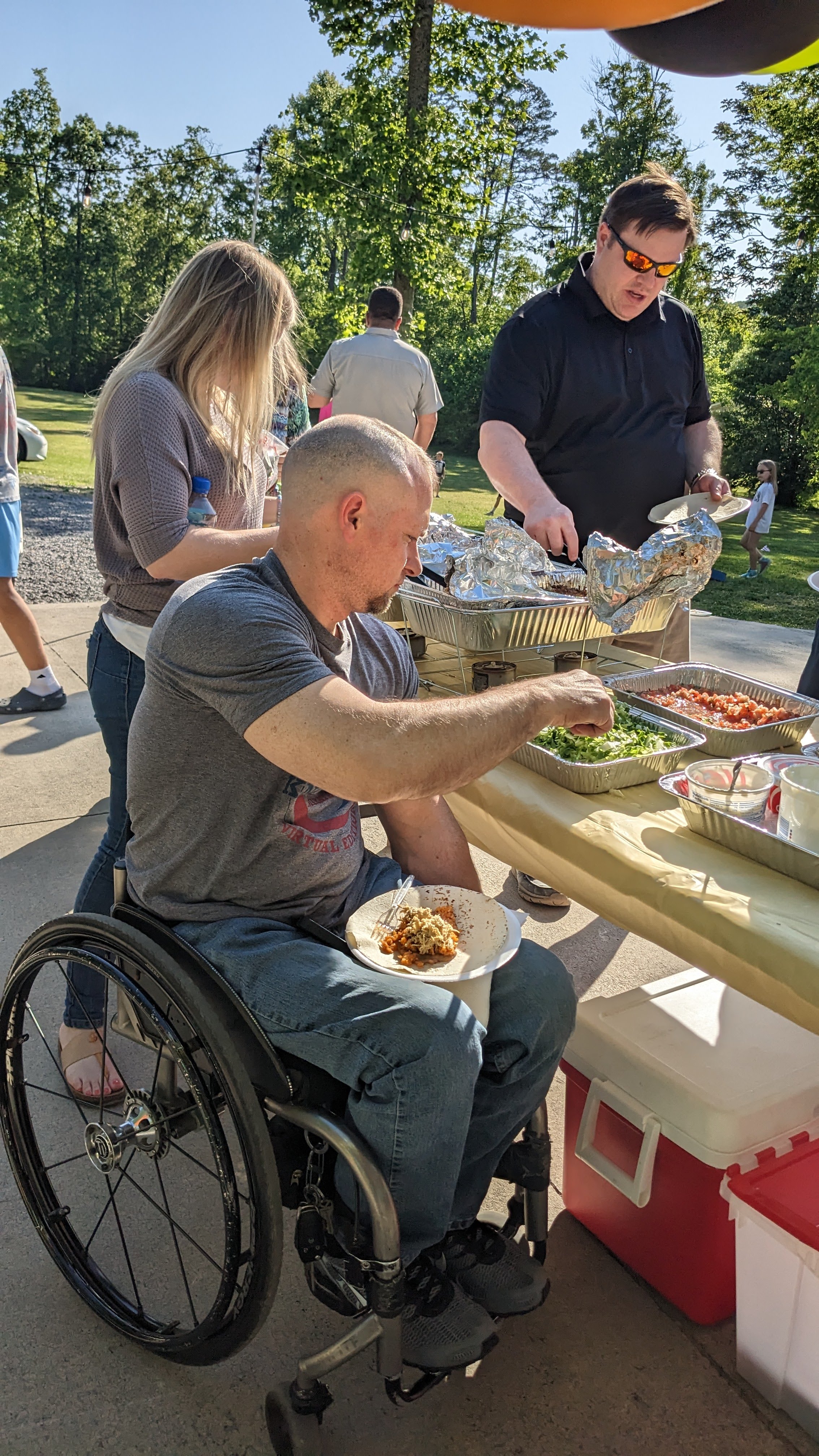 man in wheelchair serving food from outdoor buffet